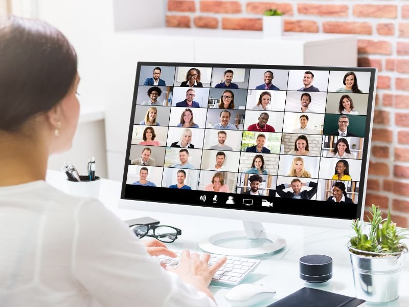 Mujer participa en una videollamada con diferentes especialistas desde su ordenador en una oficina.